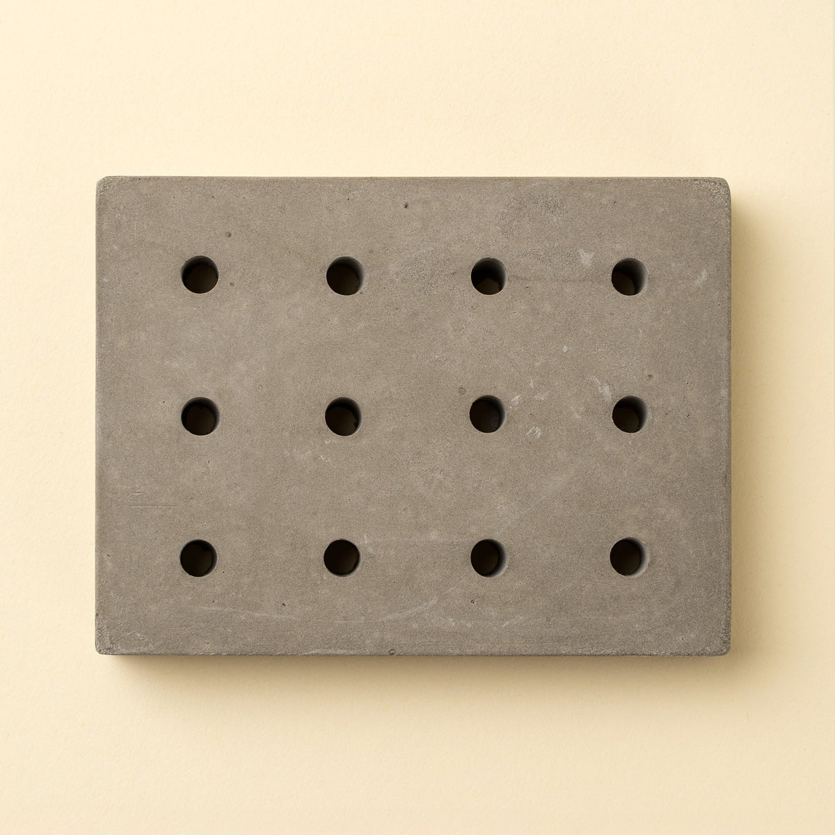 Porte-savon en béton gris rectangulaire avec trous ronds façon points