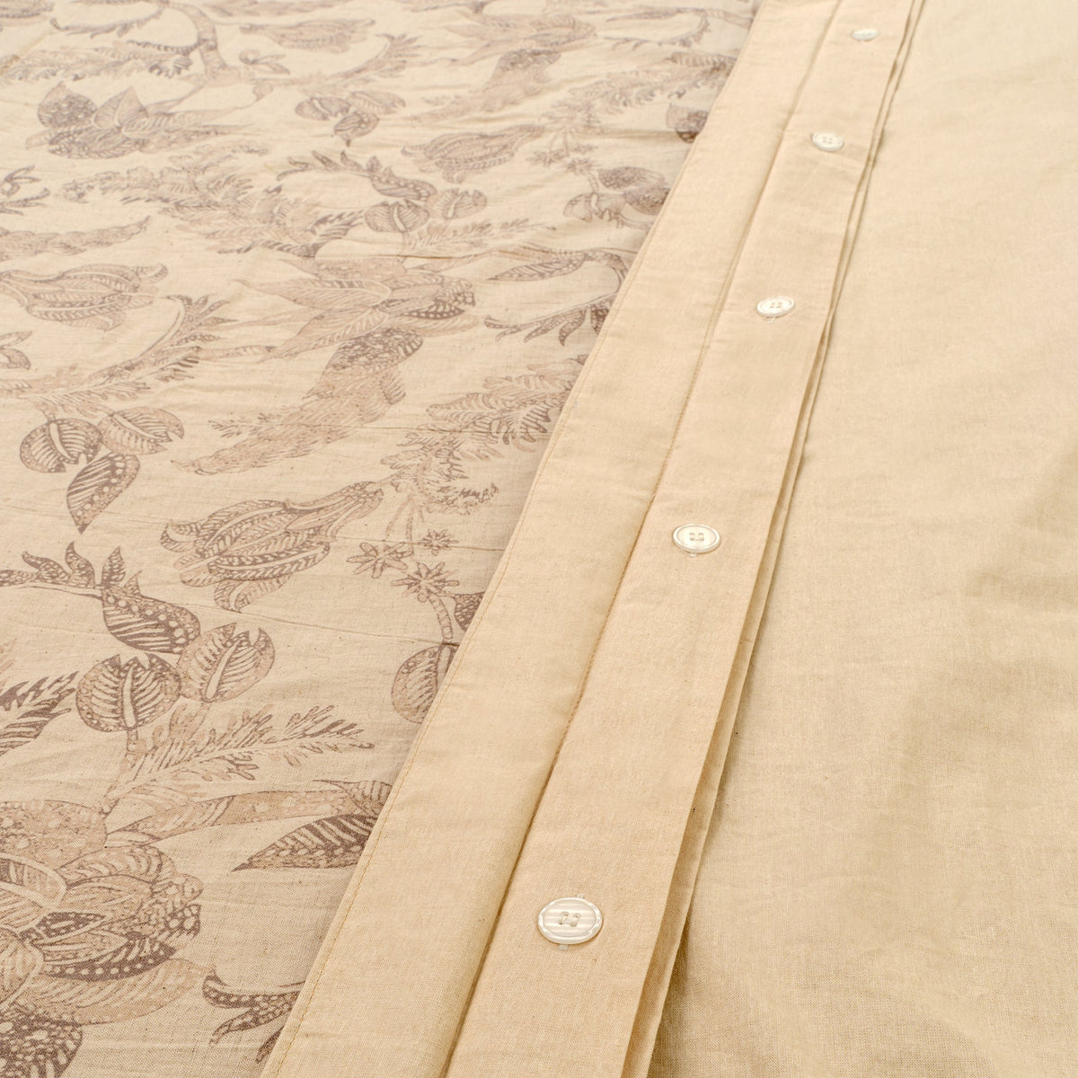 Housse de couette beige bordée, boutons visibles et motifs d’oiseaux