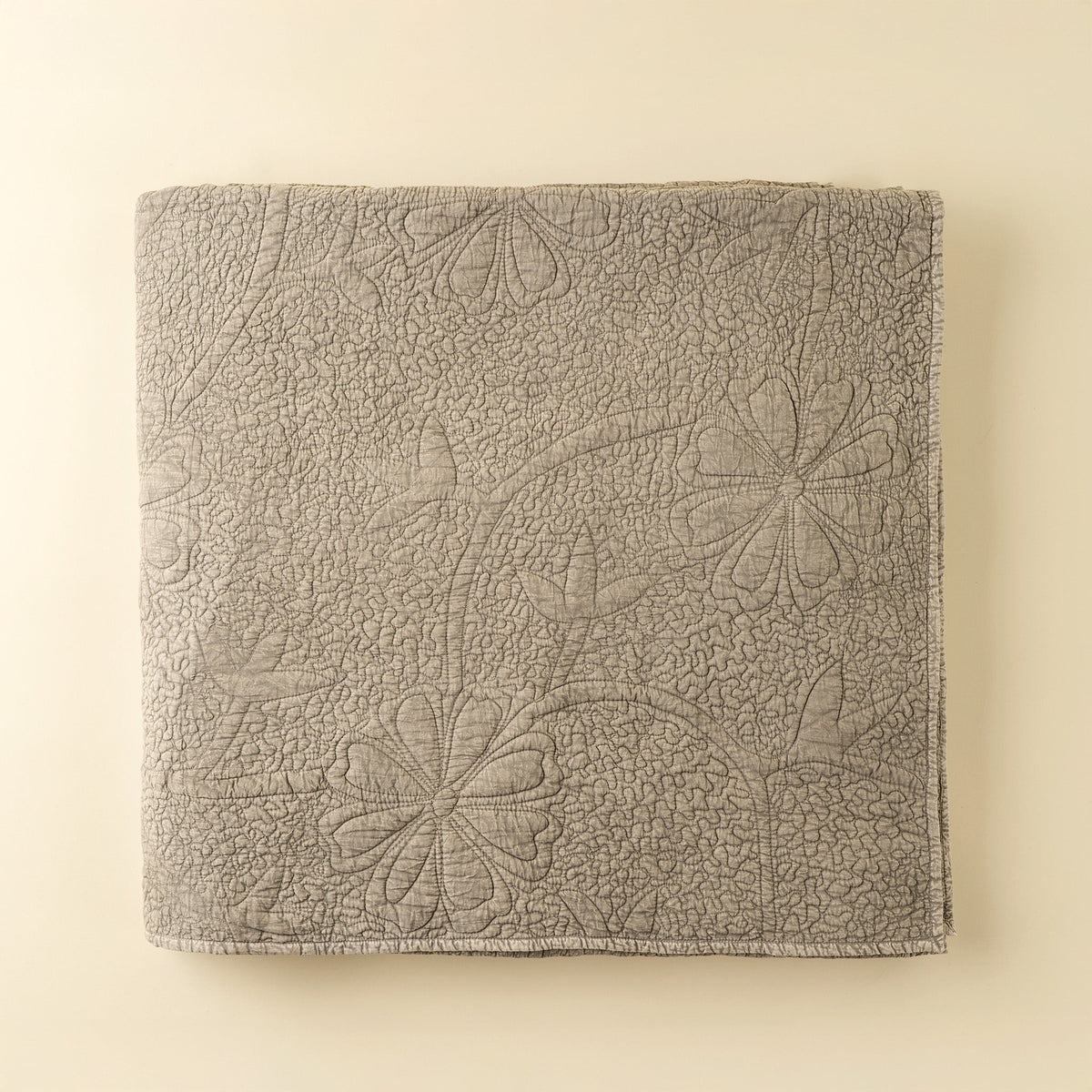 Couverture de lit matelassée beige pierre à motifs floraux en relief, rectangulaire.