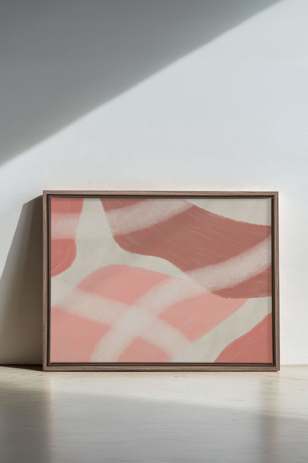 Toile étirée abstraite rose et crème, cadre brun rectangulaire sur sol