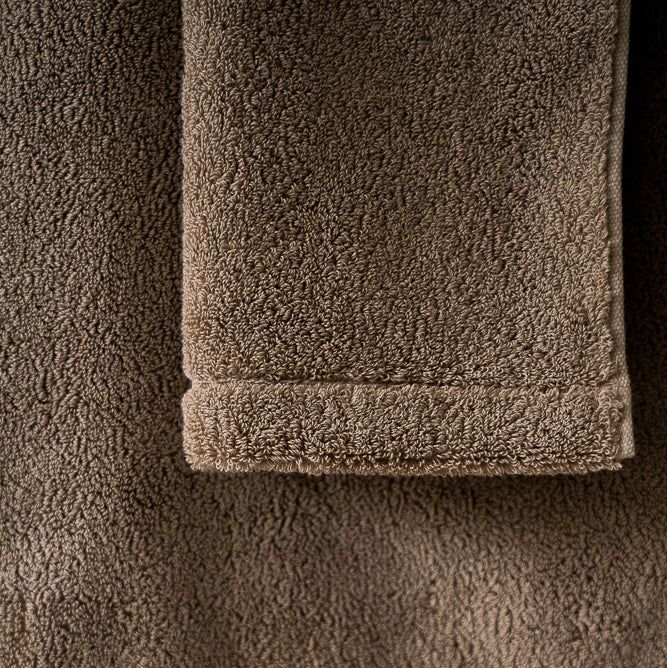 Détail d’une serviette en éponge beige clair, ourlet et texture bouclée visibles
