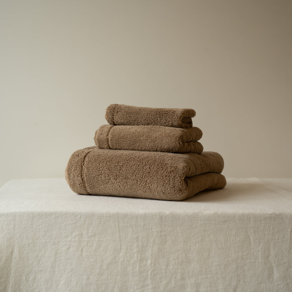 Ensemble de serviettes en éponge beige clair, trois serviettes empilées