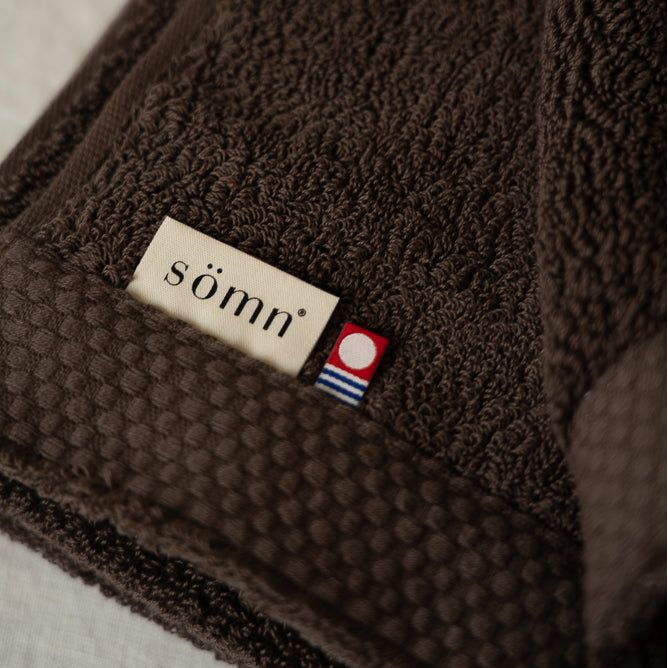 Grande serviette de bain en coton brun foncé, avec étiquette sömn