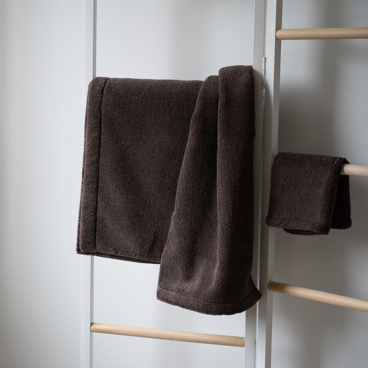 Serviettes en éponge marron foncé sur porte-serviettes, une serviette à l’avant