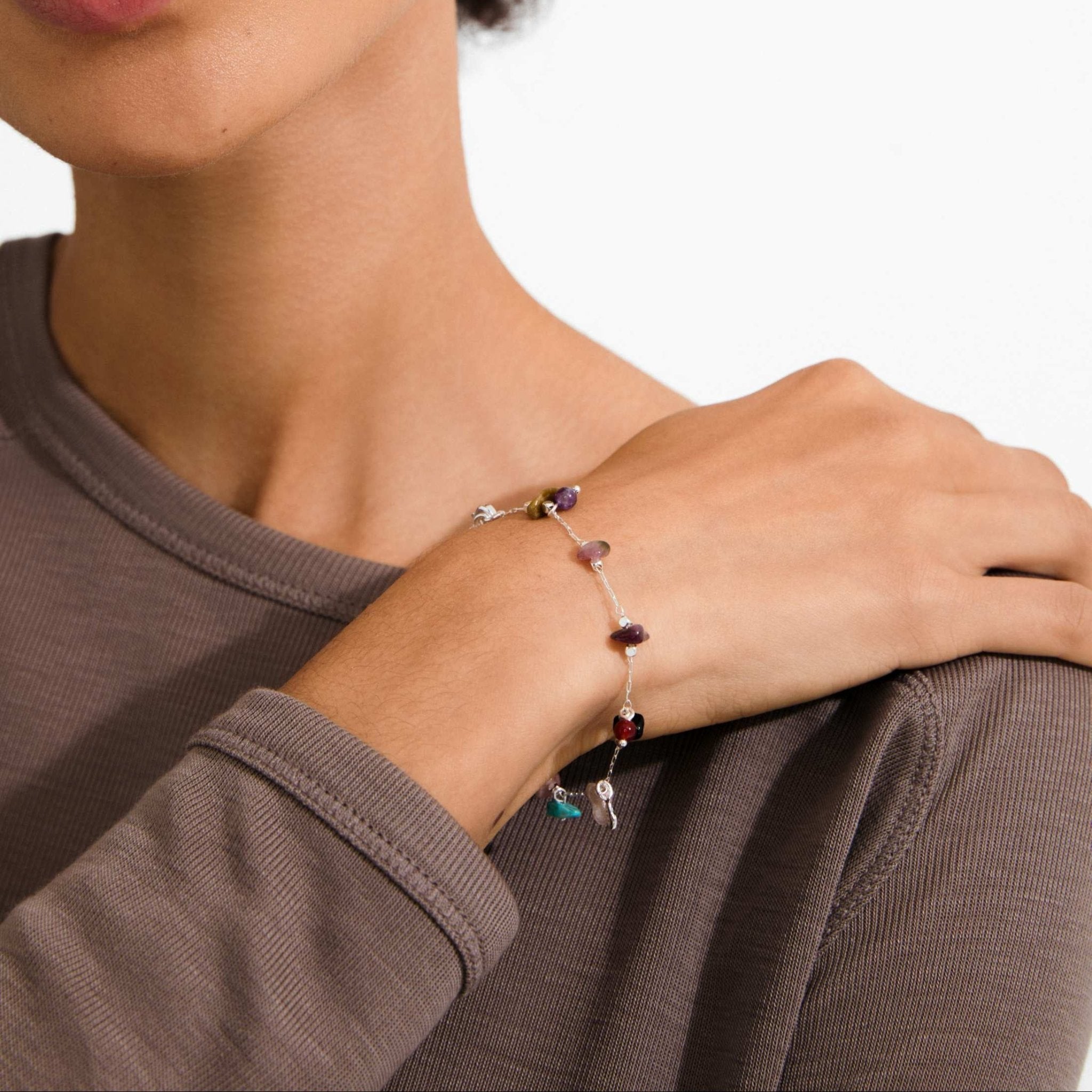 Bracelet à pierres colorées au poignet, petites breloques sur chaîne fine