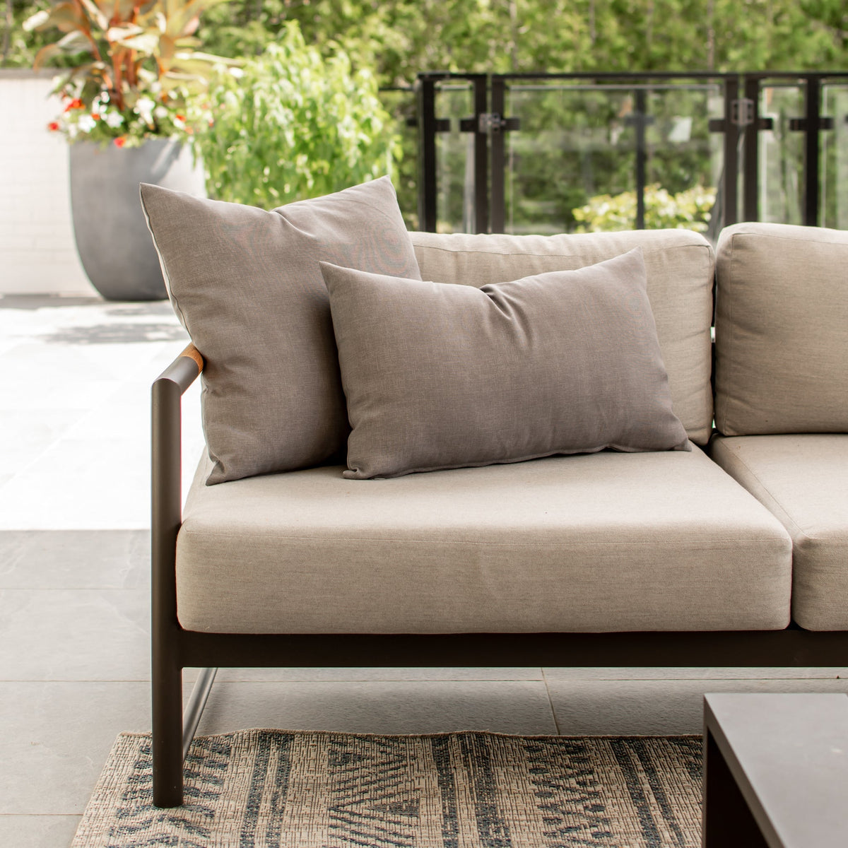 Coussin d'extérieur gris chiné de 20 x 20 pouces sur un fauteuil de patio contemporain.
