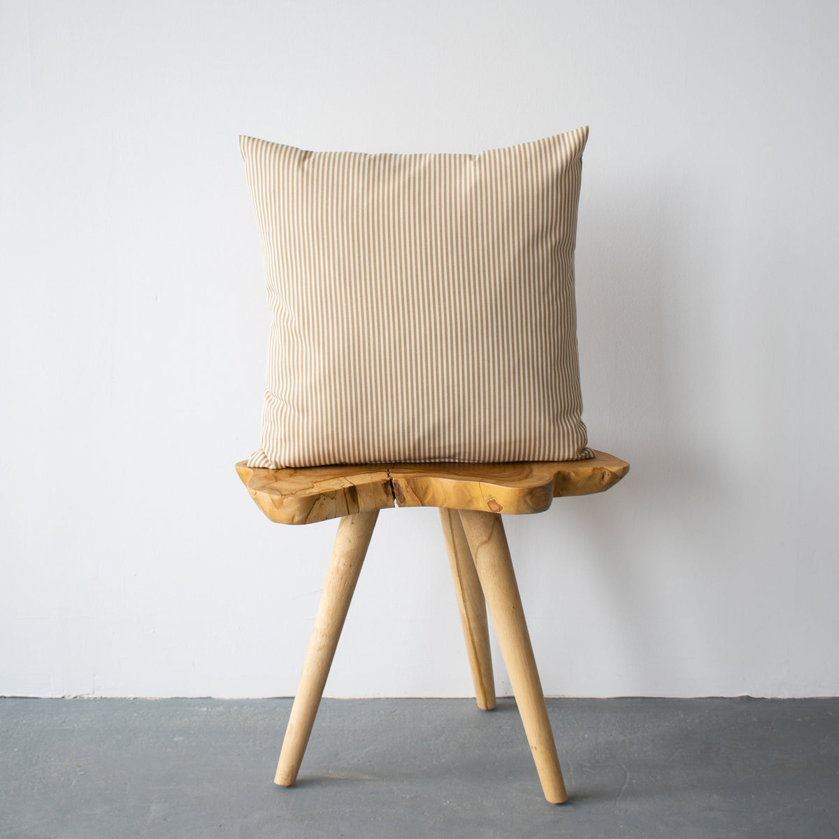 Coussin d’extérieur rayé crème et beige, carré, sur tabouret en bois, face visible