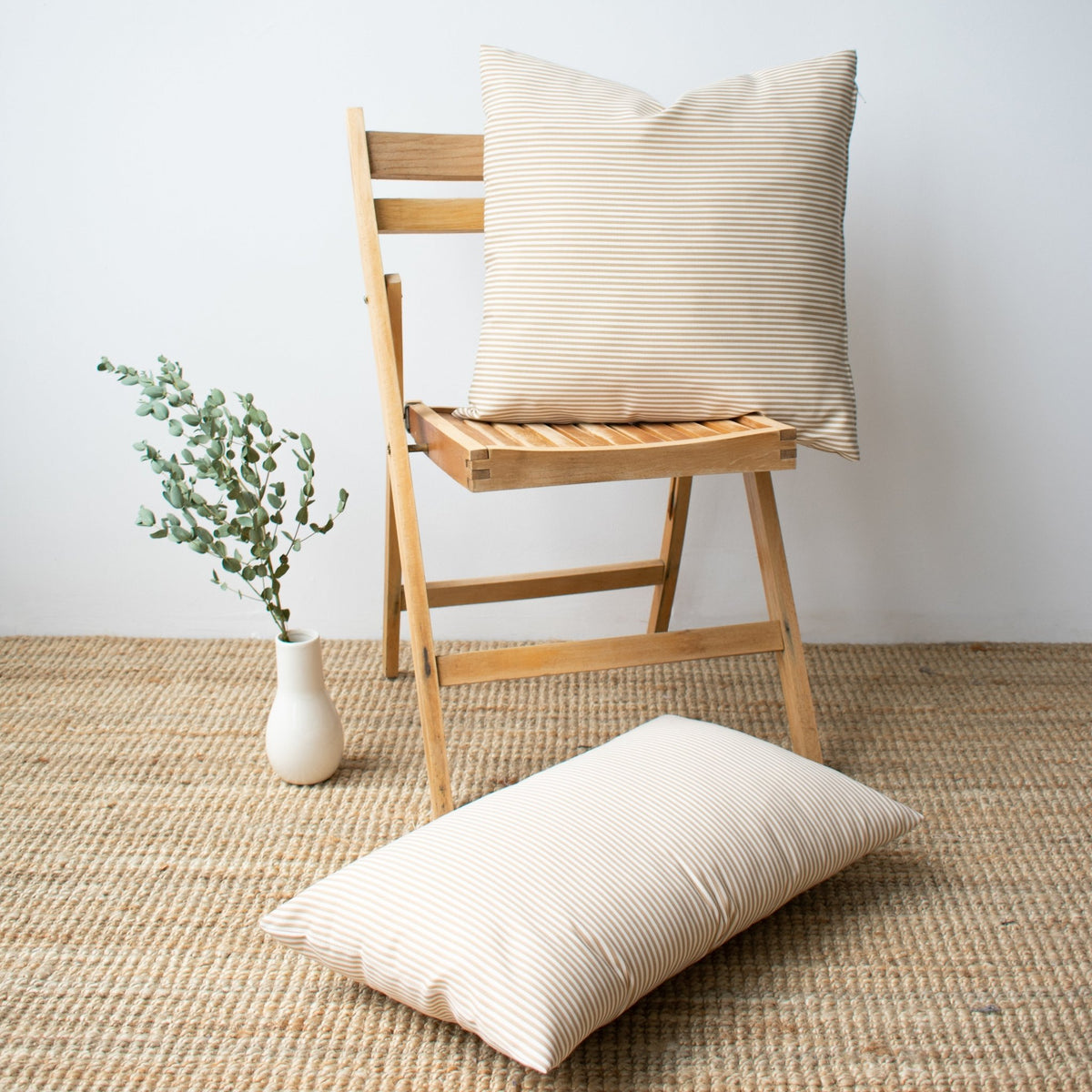 Coussin d'extérieur rayé crème et beige de 20 x 20 pouces sur un mobilier de patio élégant.