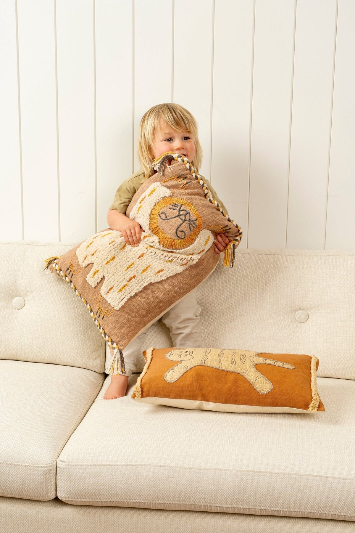 Housse de coussin coton brun avec motif lion, bord festonné et pompons aux coins