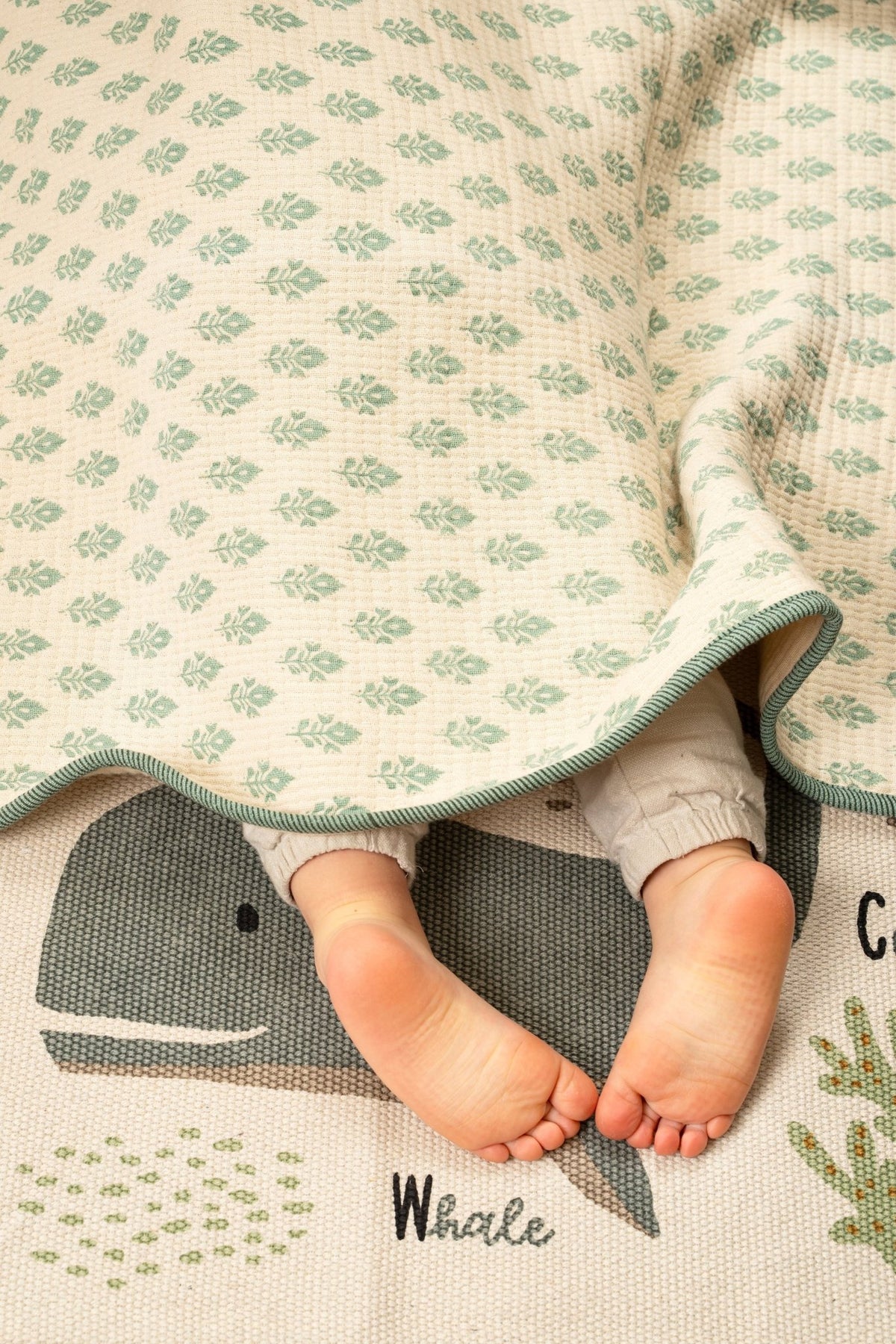 Couverture bébé en coton turquoise à motif feuilles, bordures rayées, vue rapprochée