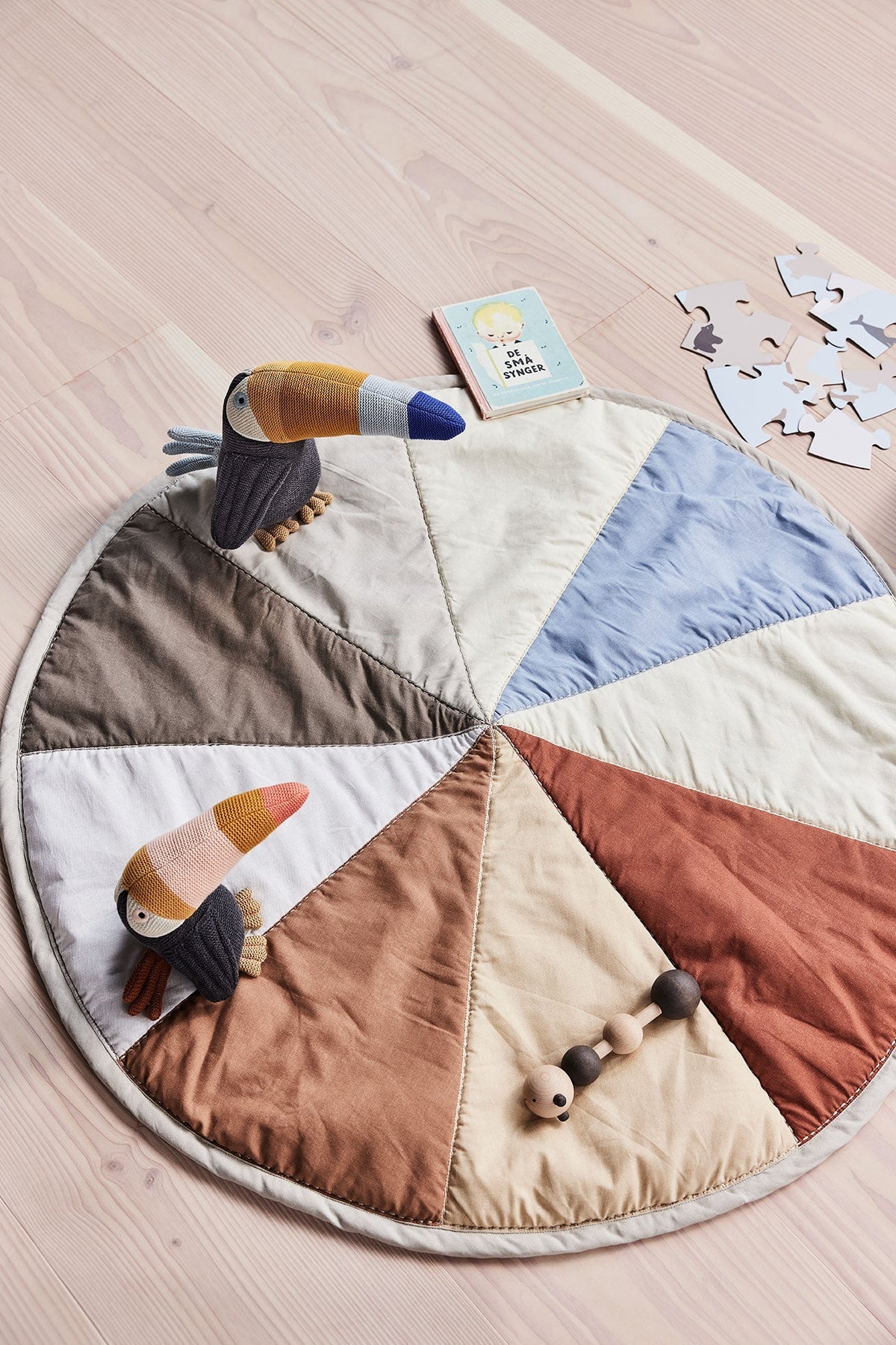 Couverture matelassée ronde réversible, patchwork triangulaire bleu, beige, brun et gris.