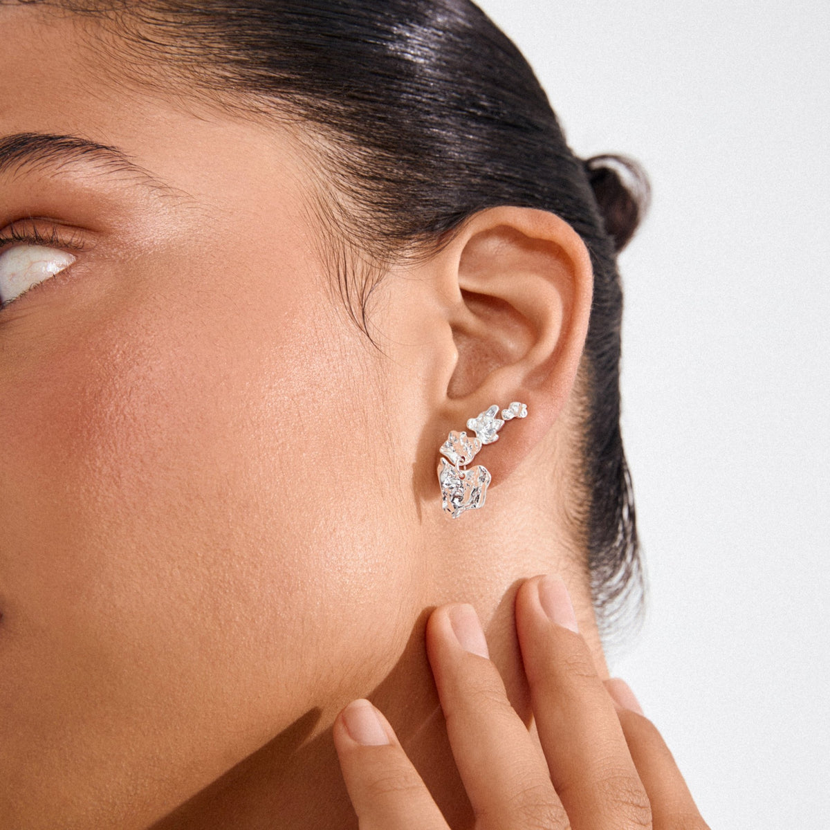 Boucles d’oreilles HORIZON 3-en-1 en cristaux, finition argentée, gros plan sur l’oreille.
