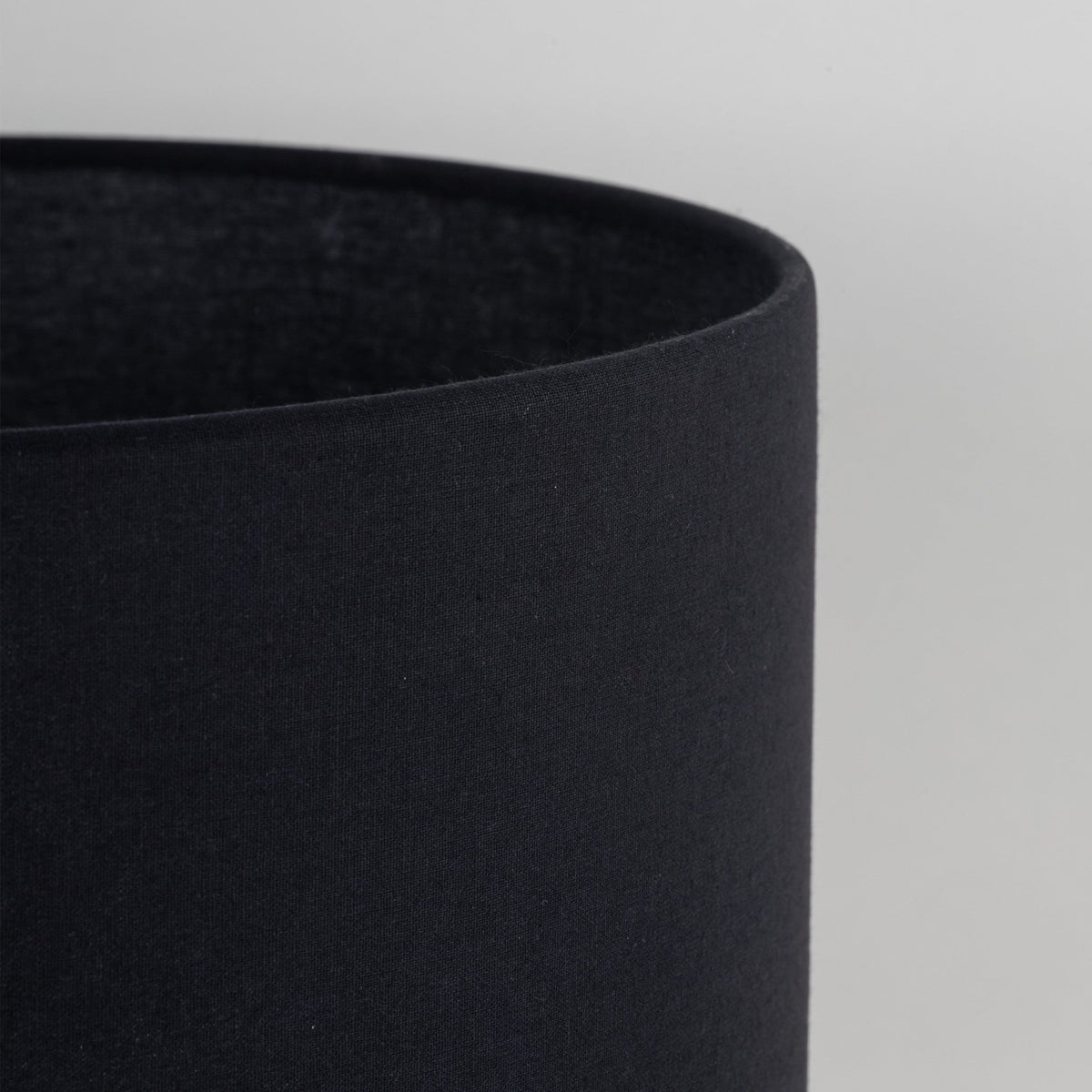 Abat-jour cylindrique en tissu noir, bord supérieur arrondi et couture visible