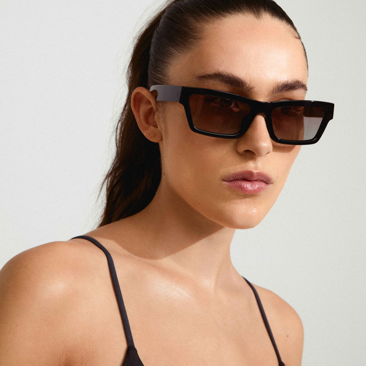 Lunettes de soleil ASHLYN noires à monture angulaire, verres teintés foncés.