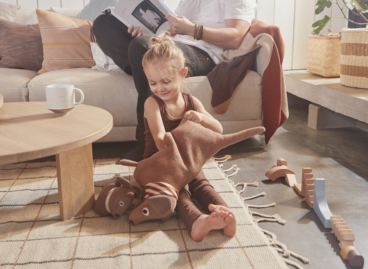 Peluche chien en tissu tricoté marron, rayures rouges et broderies, pour enfant.