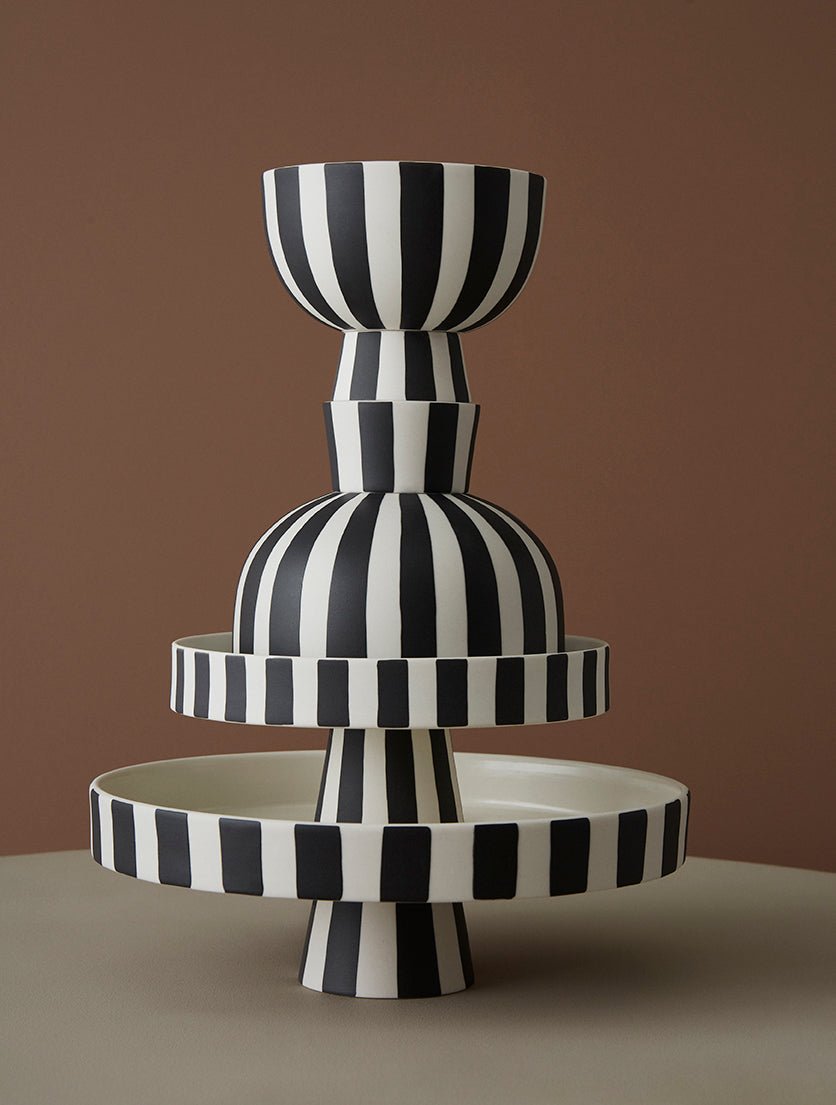 Ensemble de plateaux décoratifs en céramique à rayures noir et blanc, empilés.