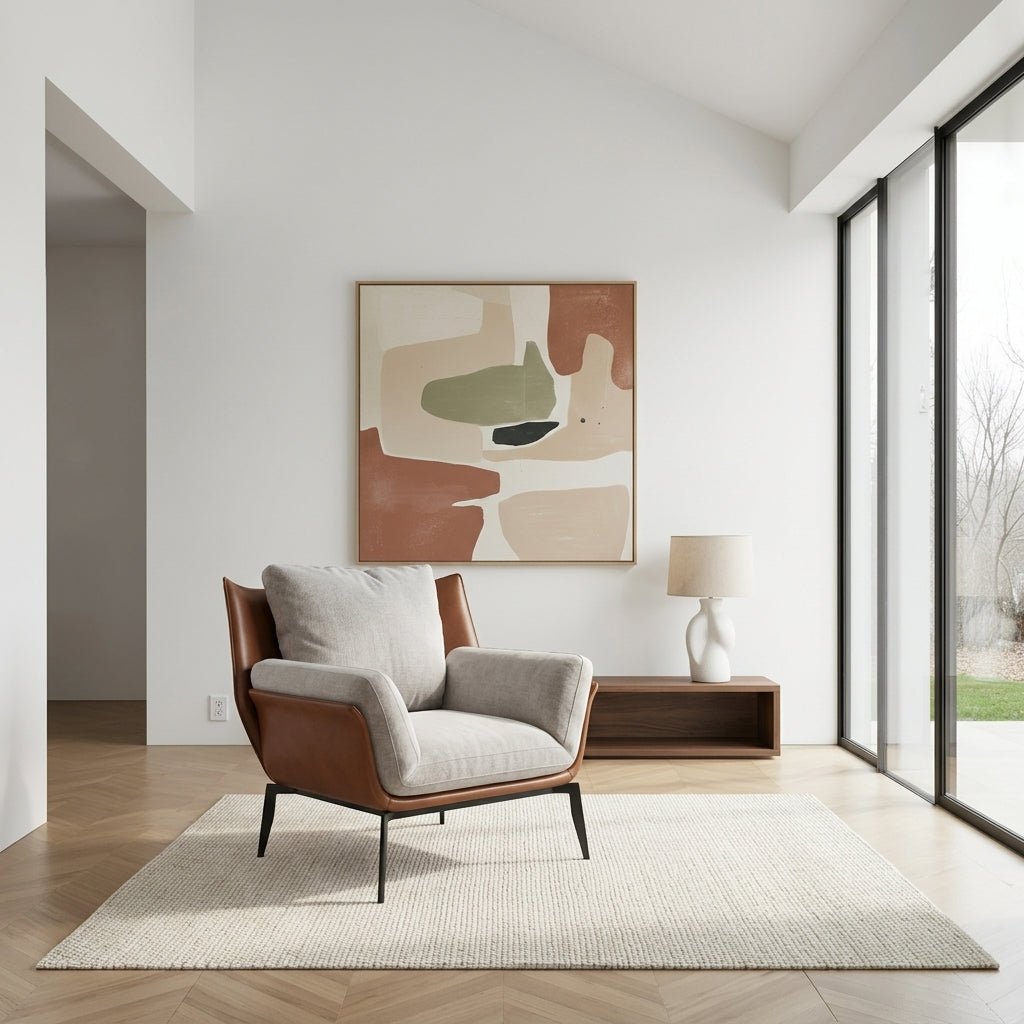 Fauteuil d’appoint gris en tissu, accoudoirs marron en cuir, pieds métalliques fins.