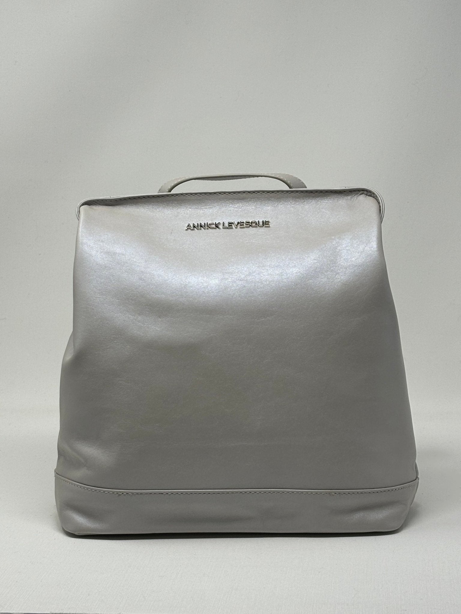 Sac à dos en cuir argent, face avant lisse et anses supérieures visibles.