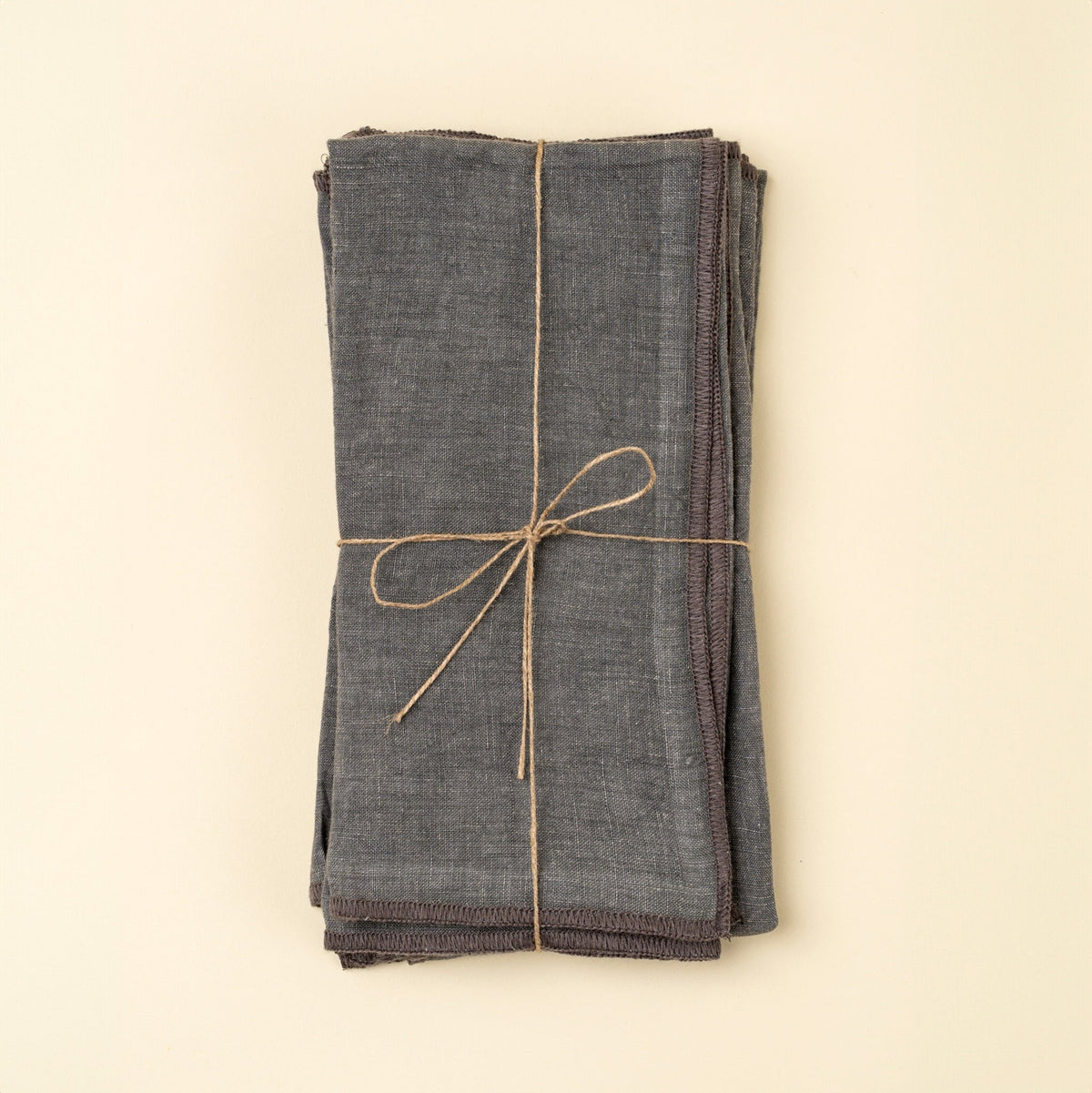 Serviettes en lin lavé bleu ardoise nouées avec un lien, bords ourlés