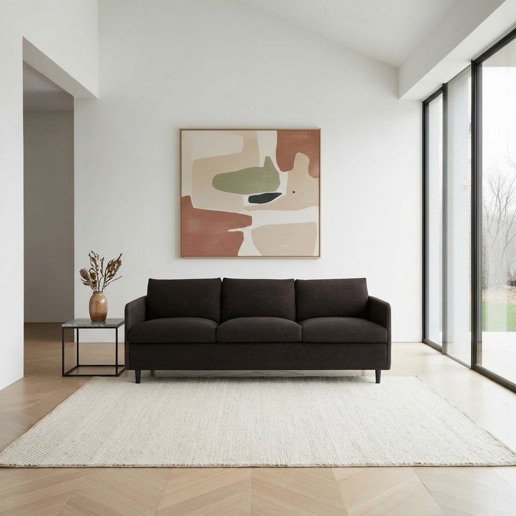 Canapé en tissu brun foncé, vue de face, assise divisée en trois coussins, pieds fins.