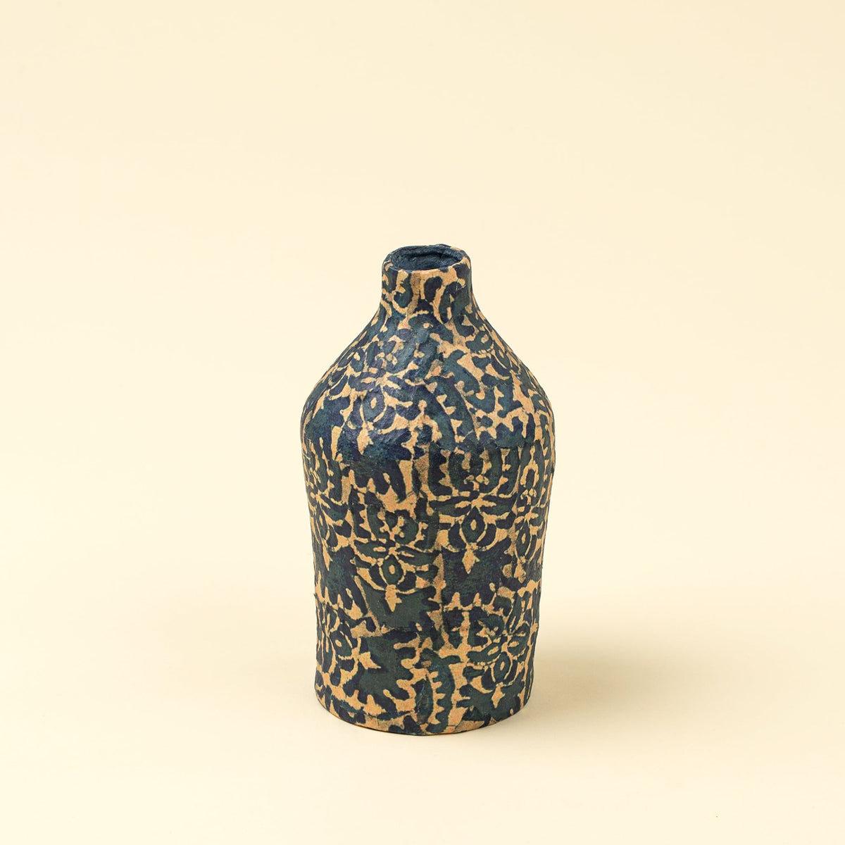 Vase-bouteille en papier mâché bleu marine et motifs beige, forme étroite.