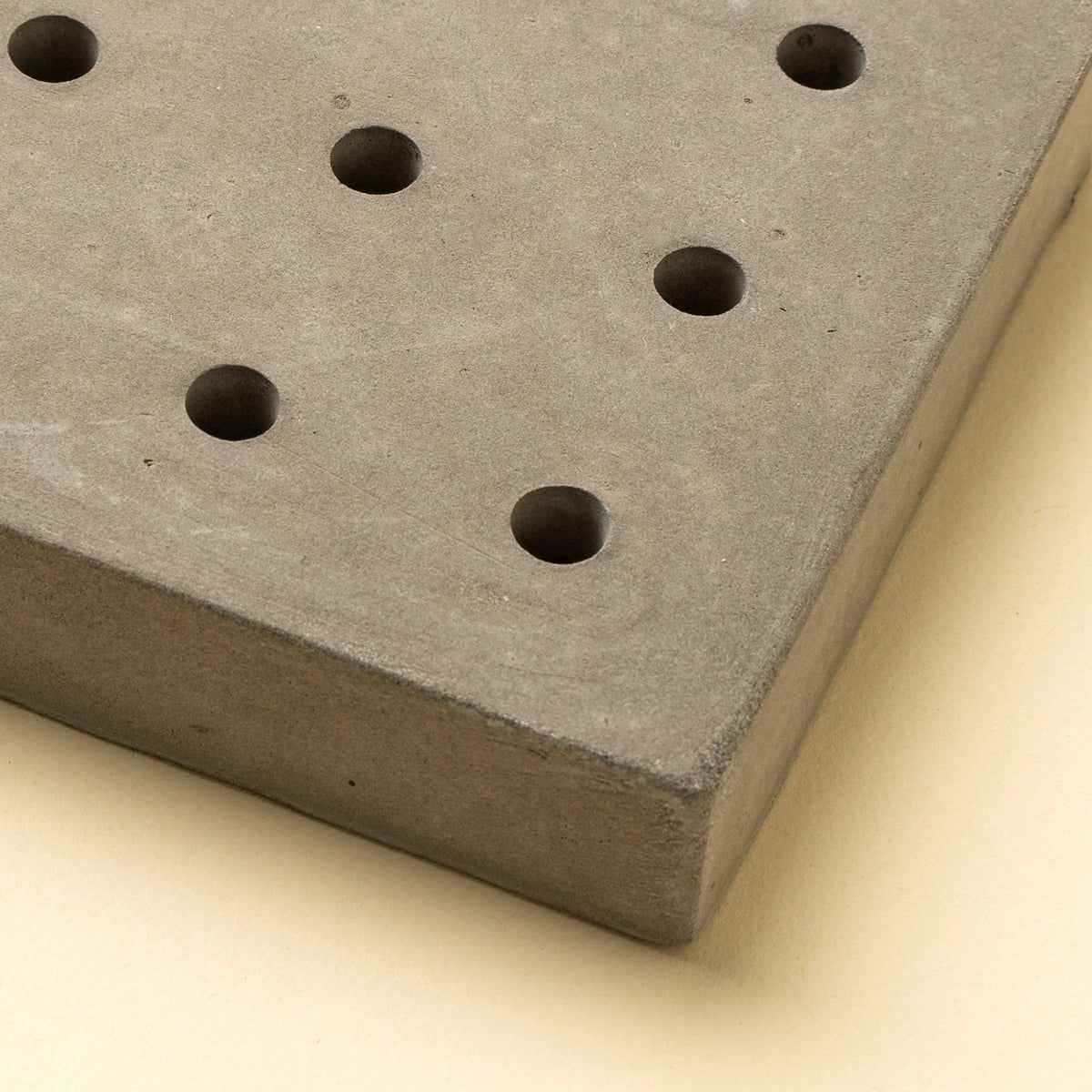 Porte-savon en béton gris à trous ronds, vue rapprochée en angle
