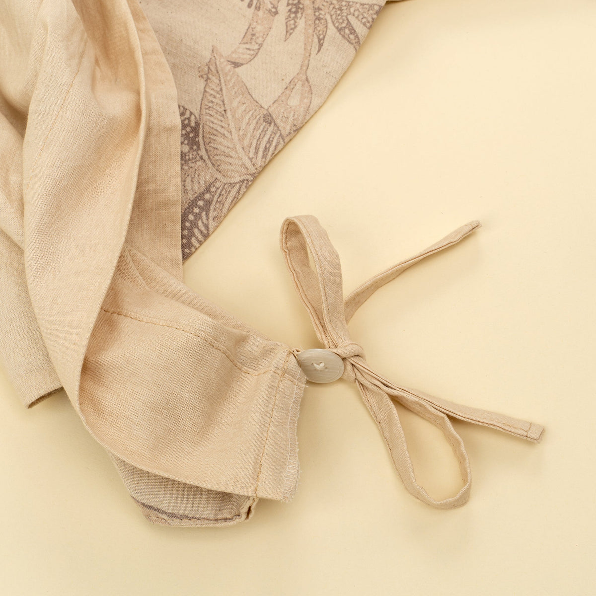 Housse de couette beige avec attache nouée et boutons sur le bord