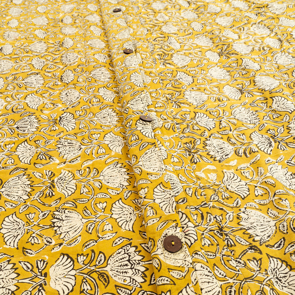 Tissu moutarde imprimé floral blanc, boutons ronds visibles sur la housse