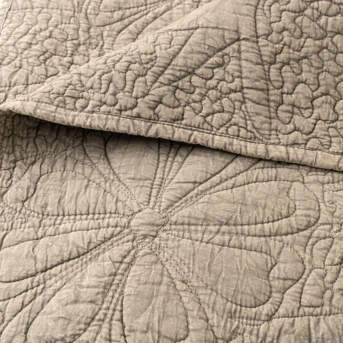 Couverture de lit matelassée beige pierre, texture en relief avec tracés floraux au quilting.