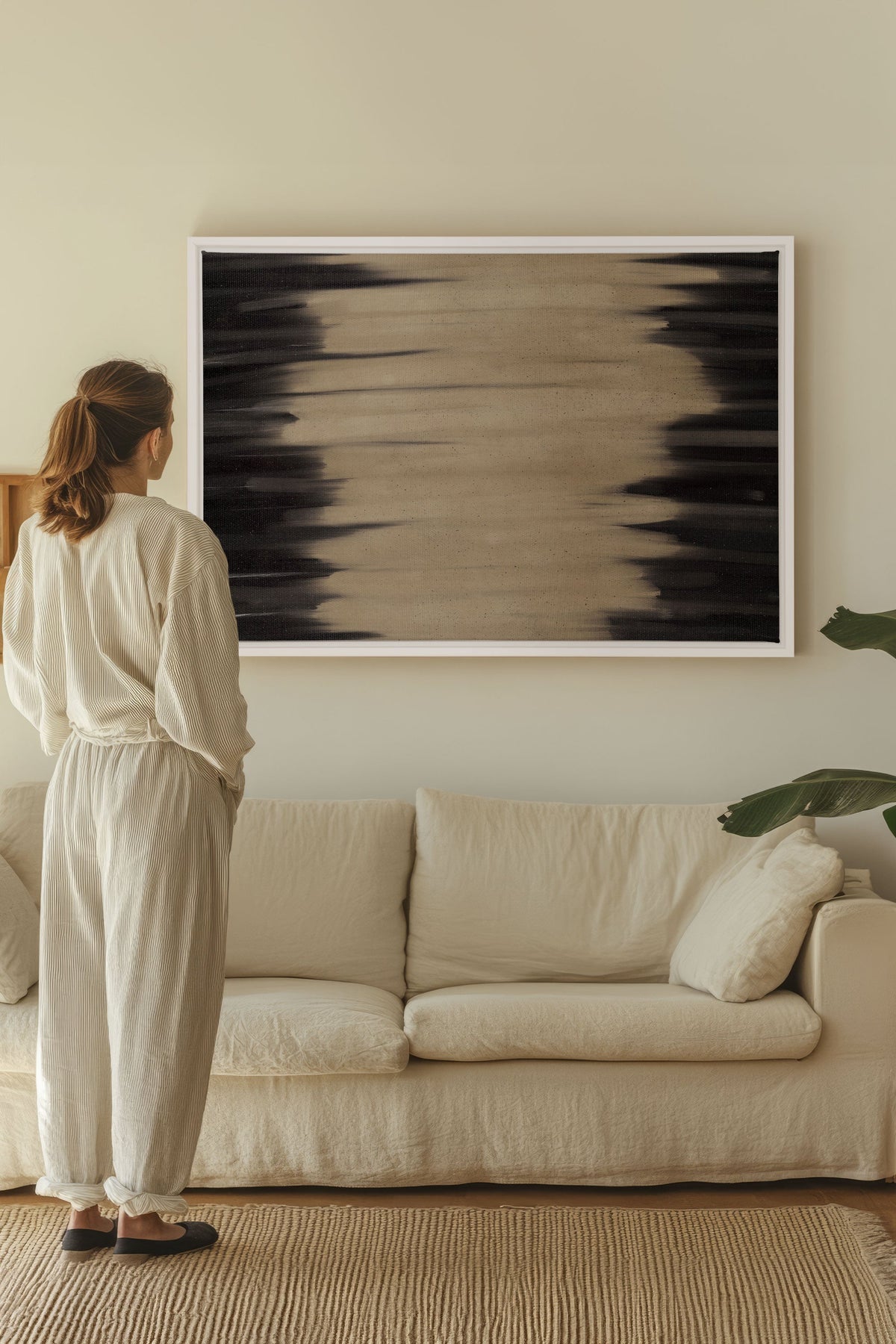 Œuvre sur toile étirée encadrée blanc, composition abstraite noir sur fond beige.