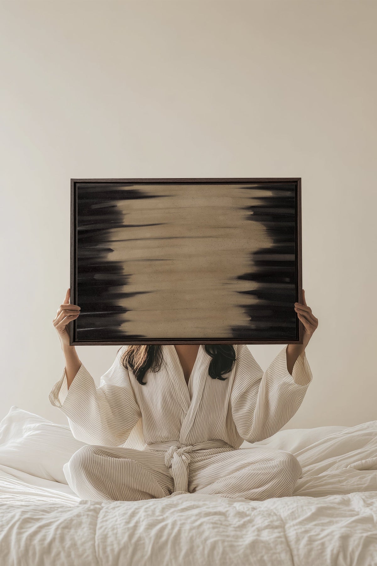 Œuvre sur toile étirée encadrée, motif abstrait noir et beige tenue au-dessus du lit.