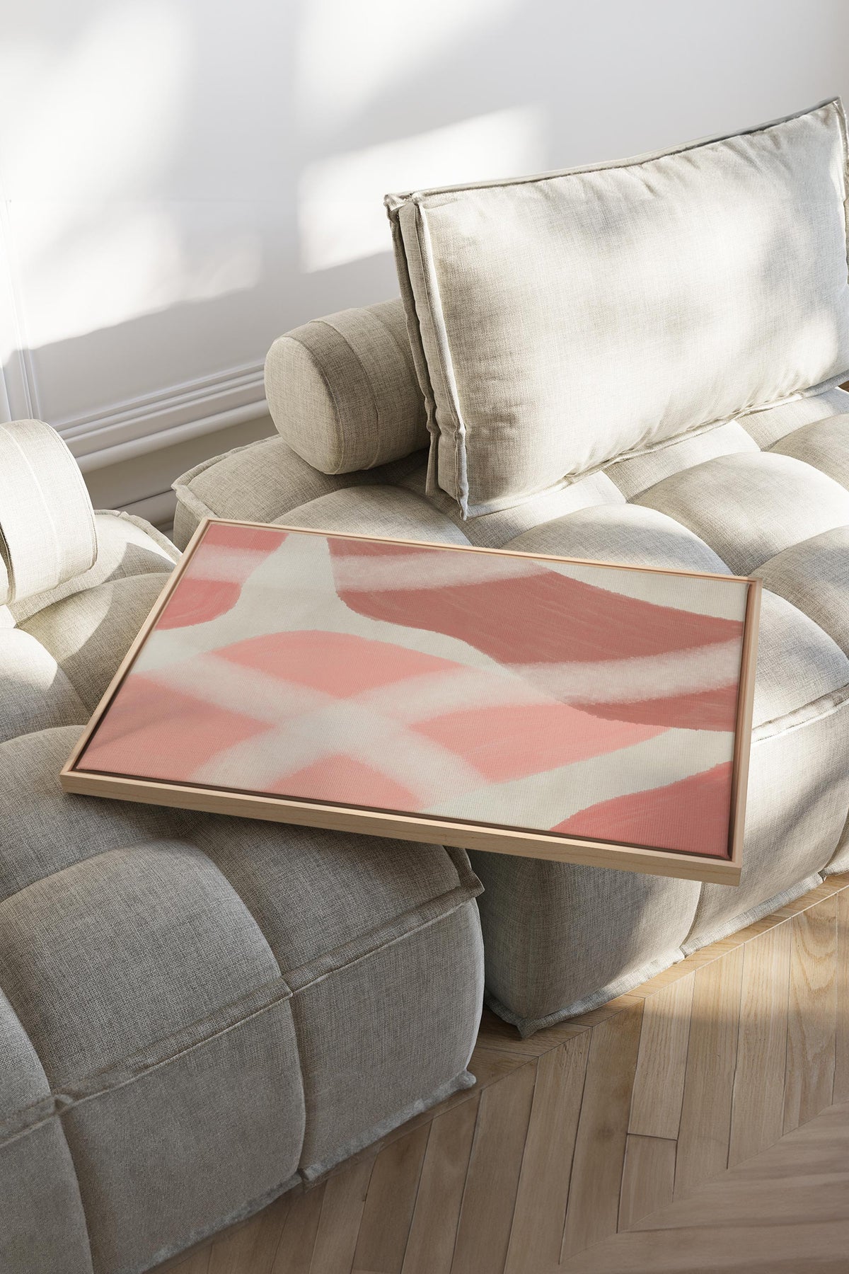 Toile étirée abstraite rose et crème posée sur canapé, bords de toile visibles