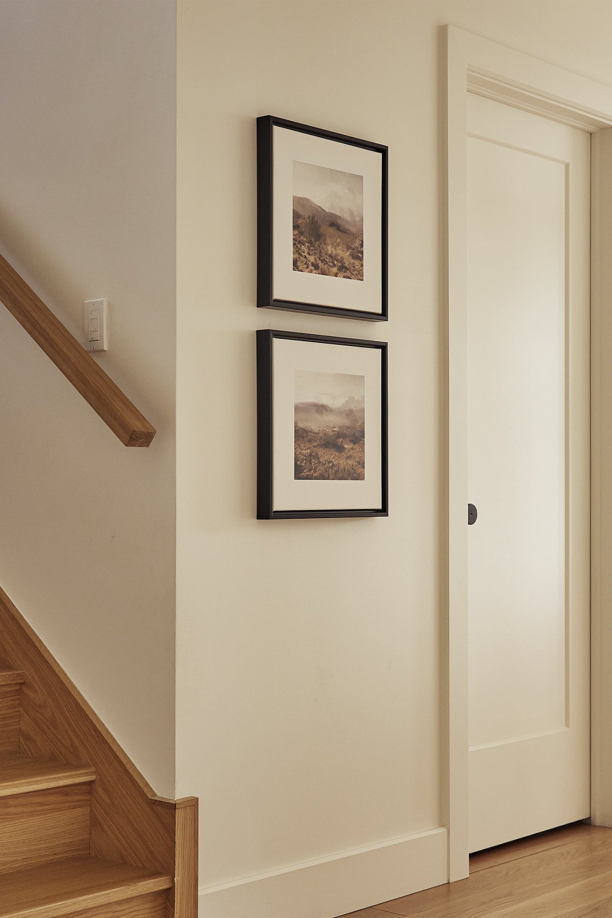 Deux tableaux toile étirée encadrés noirs, paysages sur un mur intérieur clair.