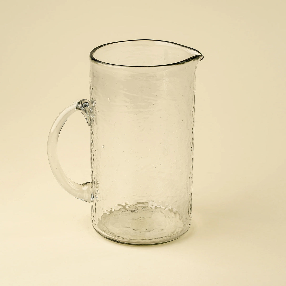 Pichet en verre soufflé transparent avec anse ronde et texture martelée