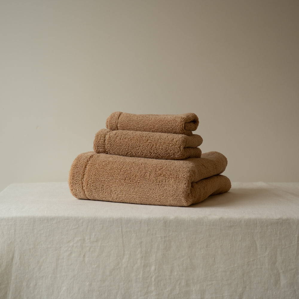 Ensemble de serviettes en éponge beige, trois serviettes empilées