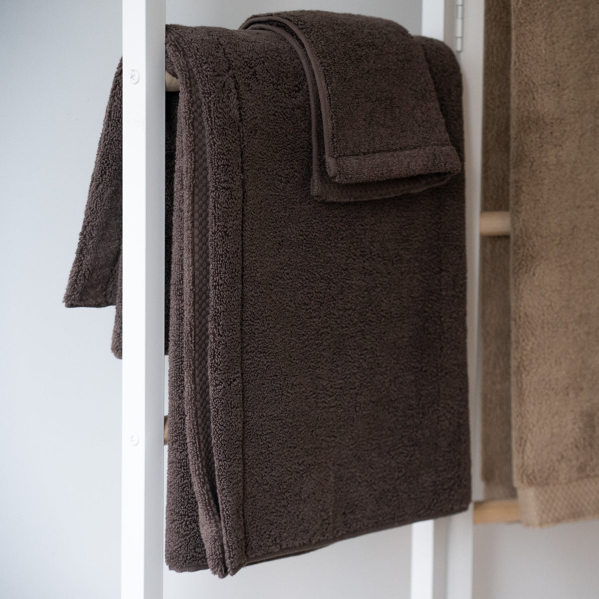 Serviette de bain en coton grand format, brun foncé, pliée et suspendue