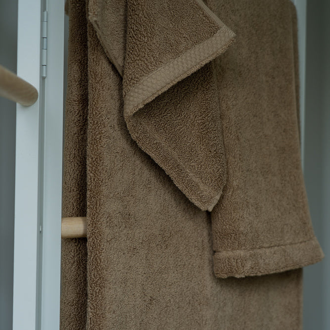 Serviette en éponge beige clair drapée sur porte-serviettes, pli visible