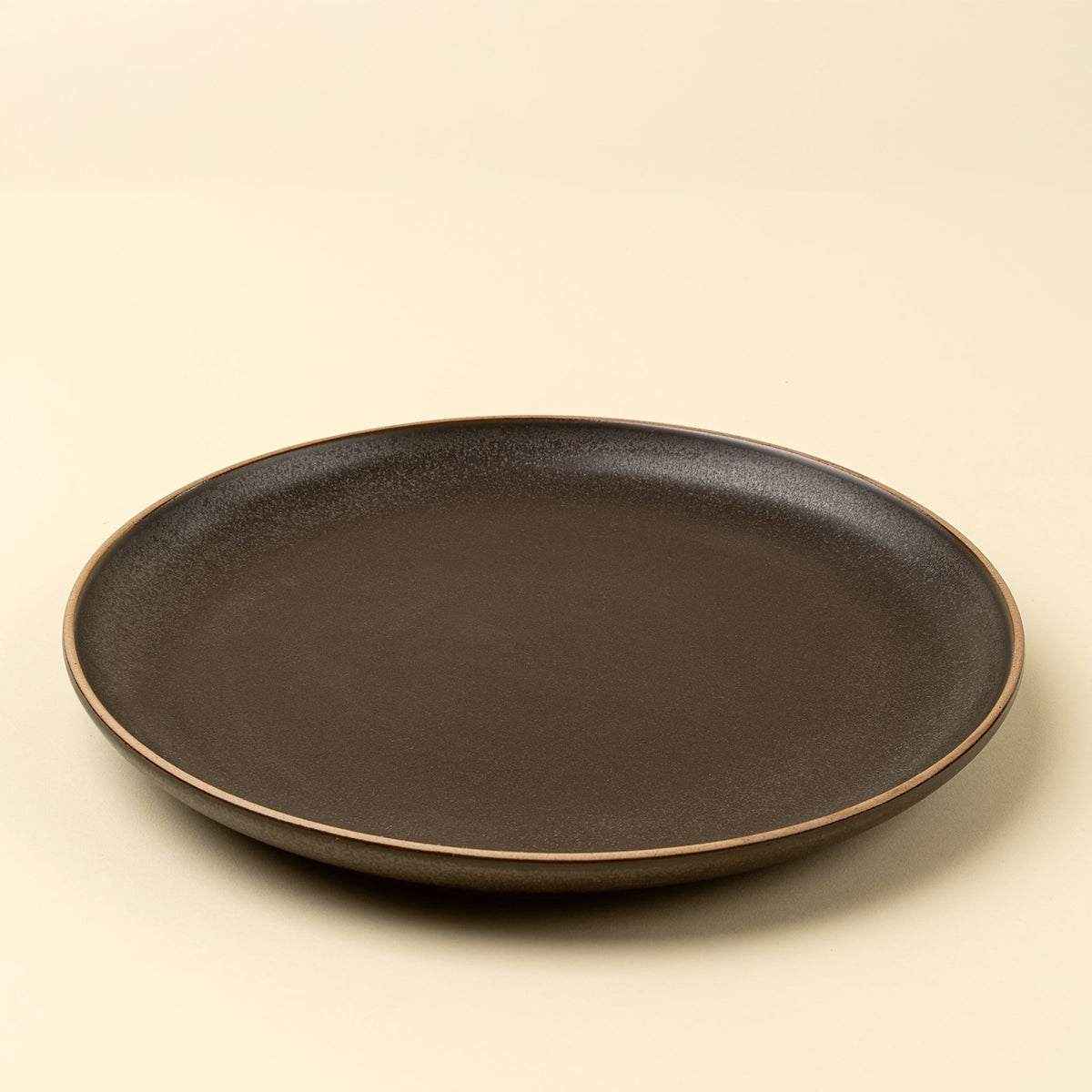 Assiette de présentation en grès couleur espresso foncé, bord fin beige