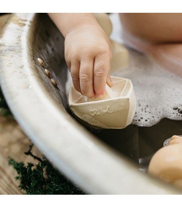 Bateau de bain origami en caoutchouc, ton vanille, tenu par un enfant