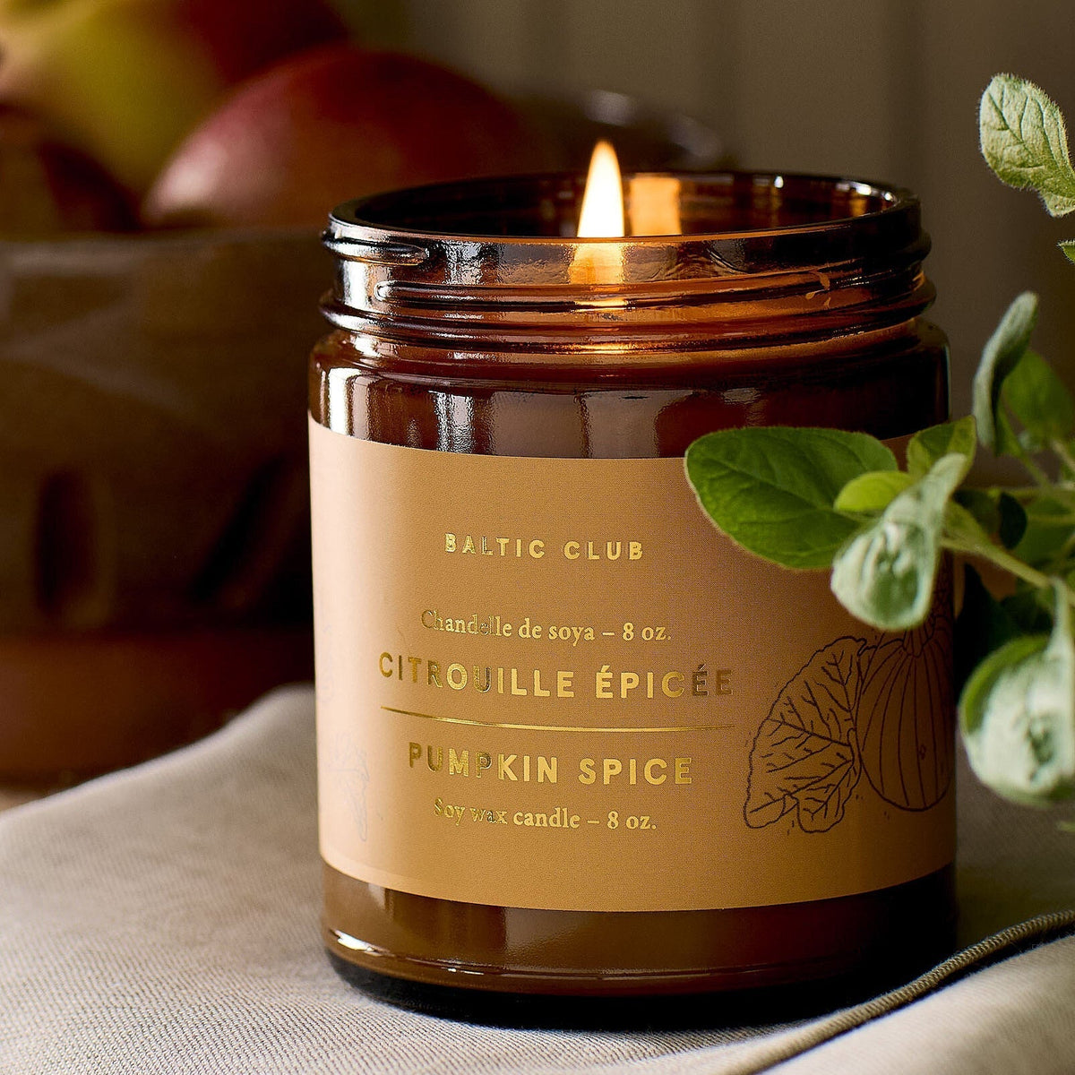 Bougie dans pot en verre ambré, bougie allumée, étiquette « Citrouille Épicée »