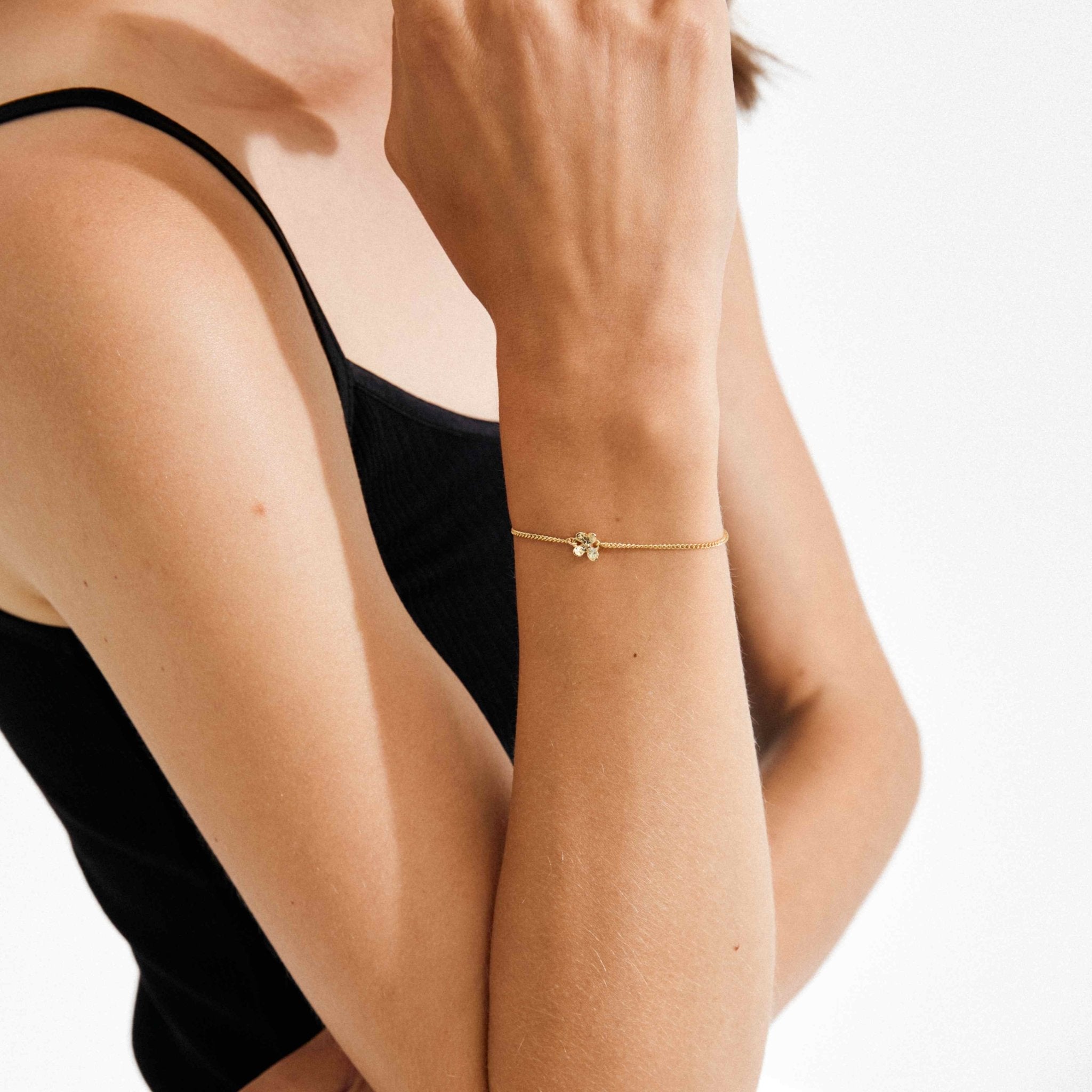Bracelet plaqué or fin avec breloque fleur centrale, ajustable, porté au poignet