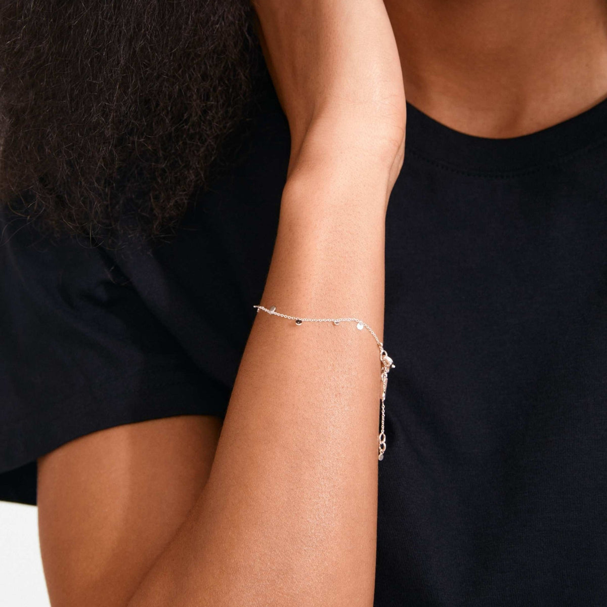 Bracelet plaqué argent à petites mailles et breloques, porté sur le bras