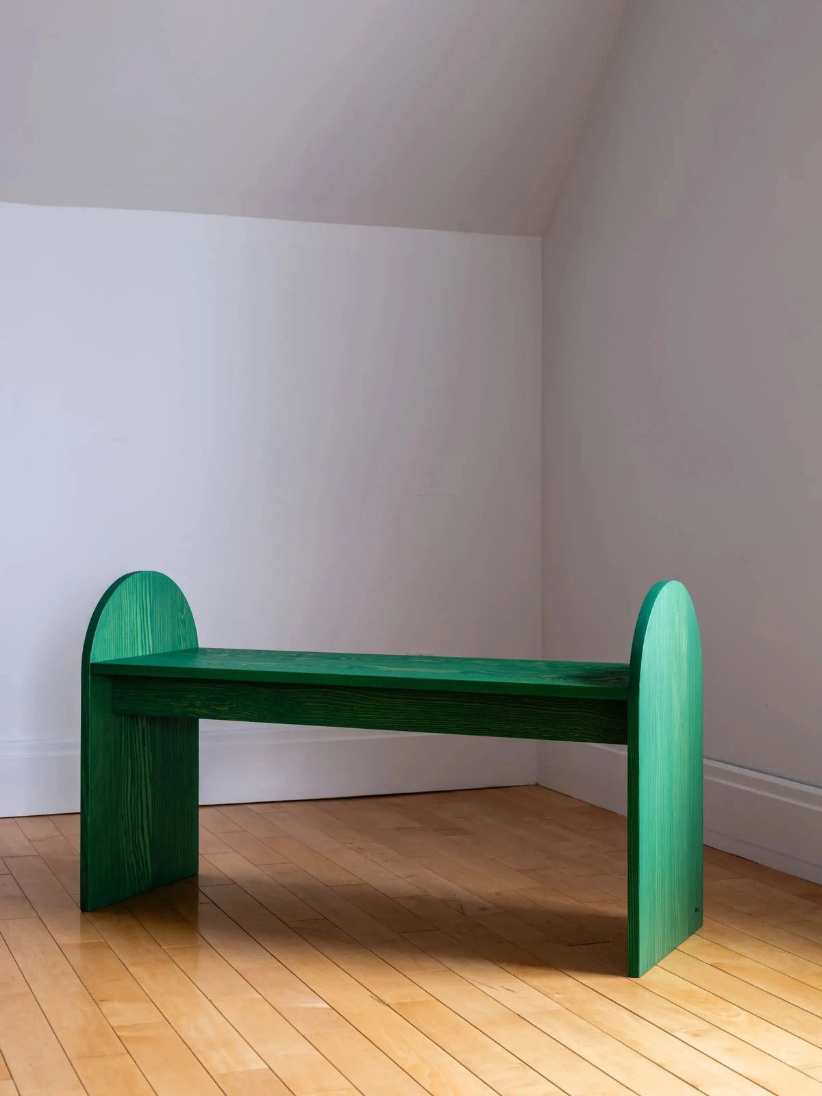 Banc d’entrée en bois vert, dossier arrondi et assise rectangulaire sur pieds épais.