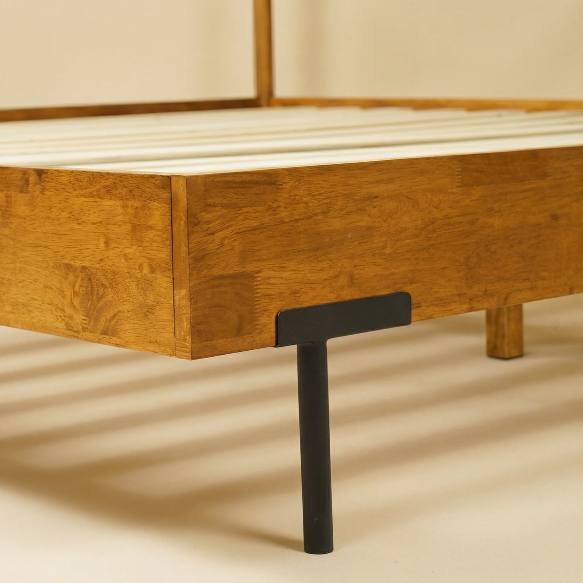 Cadre de lit en bois caramel, vue latérale avec pied noir et barre de maintien