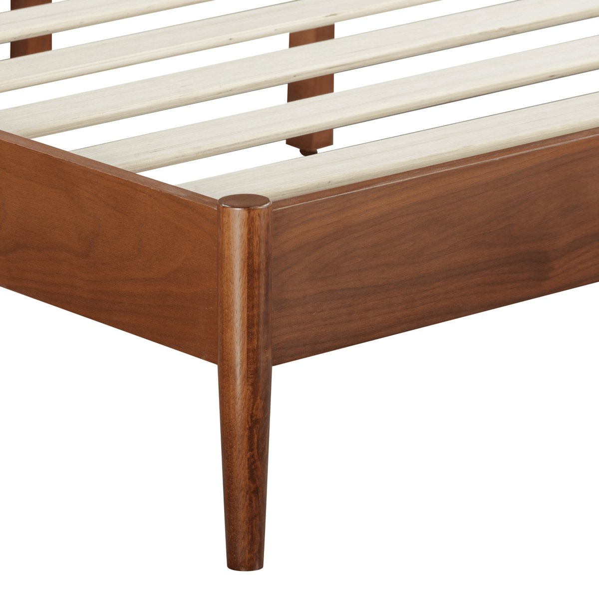Détail du cadre en bois foncé et pieds du lit, avec lattes blanches du sommier.