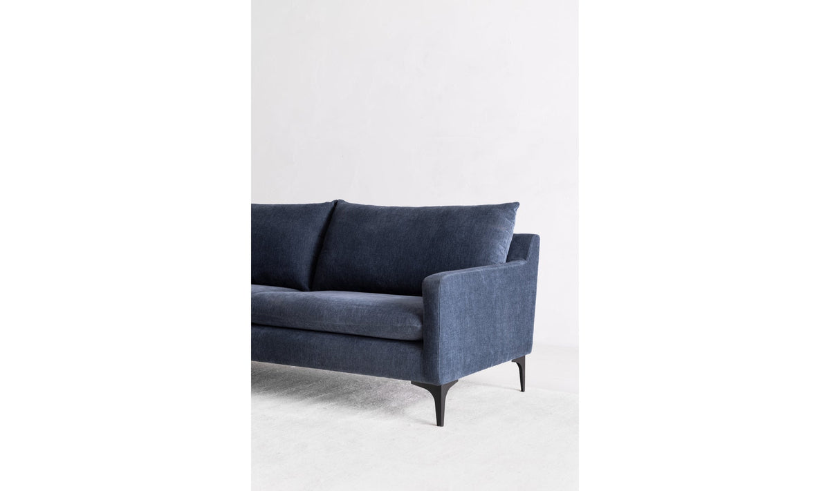 Canapé bleu en tissu, accoudoir et dossier, pieds noirs, vue en angle.