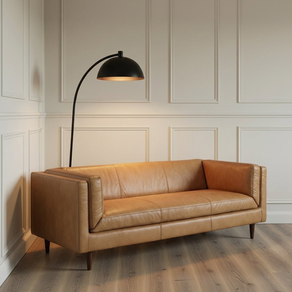 Canapé en cuir brun clair, assise capitonnée, accoudoirs intégrés, pieds fins