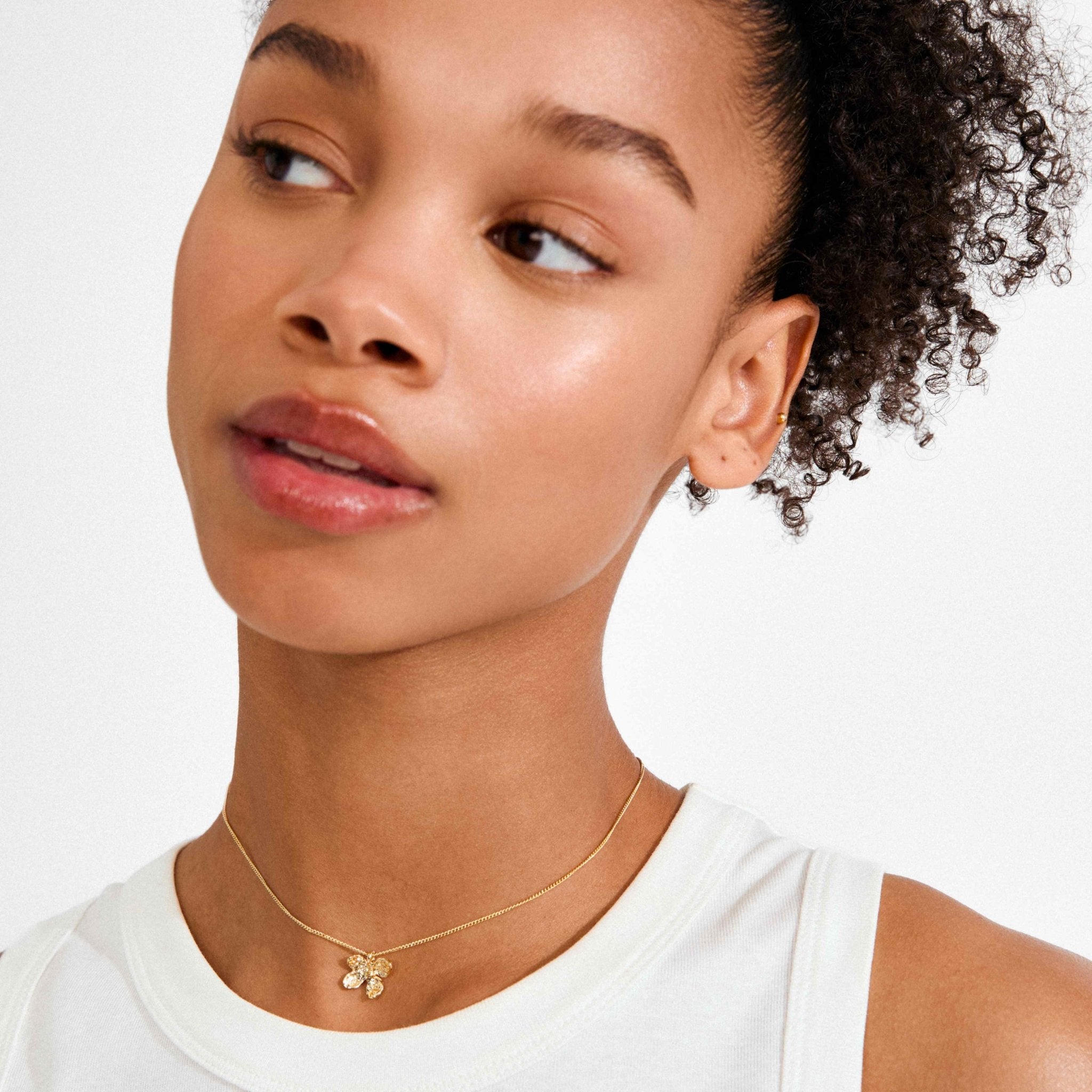 Collier plaqué or avec pendentif fleur au ras du cou, porté près du col