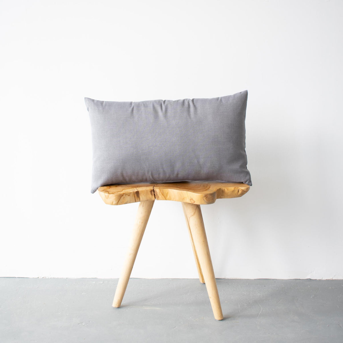 Coussin d'extérieur gris chiné au format lombaire sur un mobilier de patio contemporain.