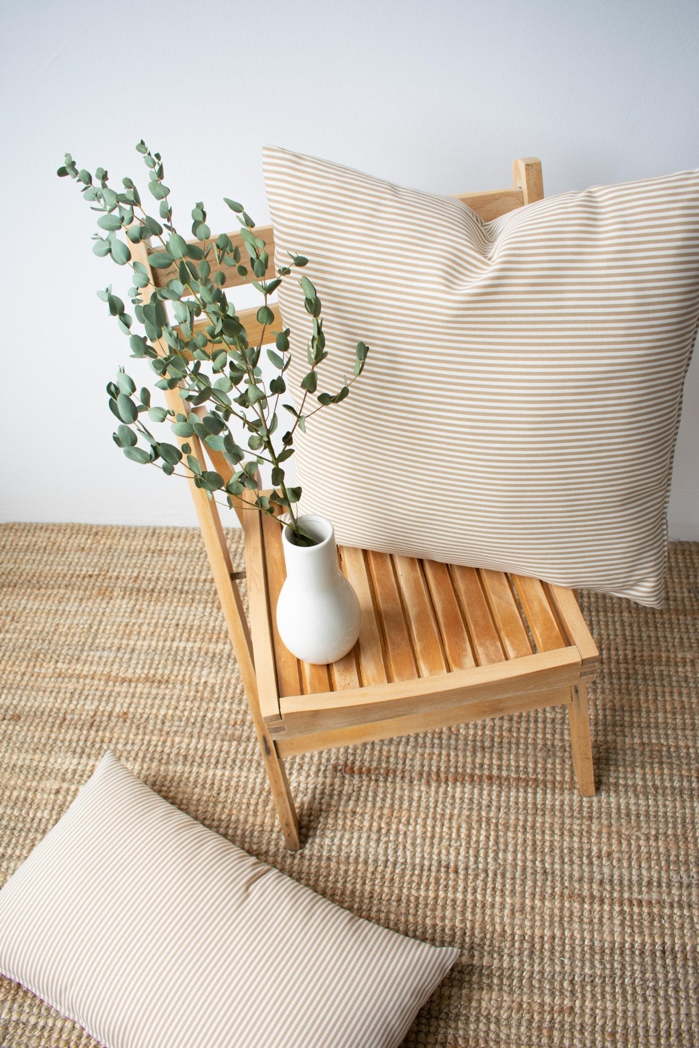 Coussin d’extérieur rayé crème et beige, posé sur fauteuil en bois, vue d’ensemble